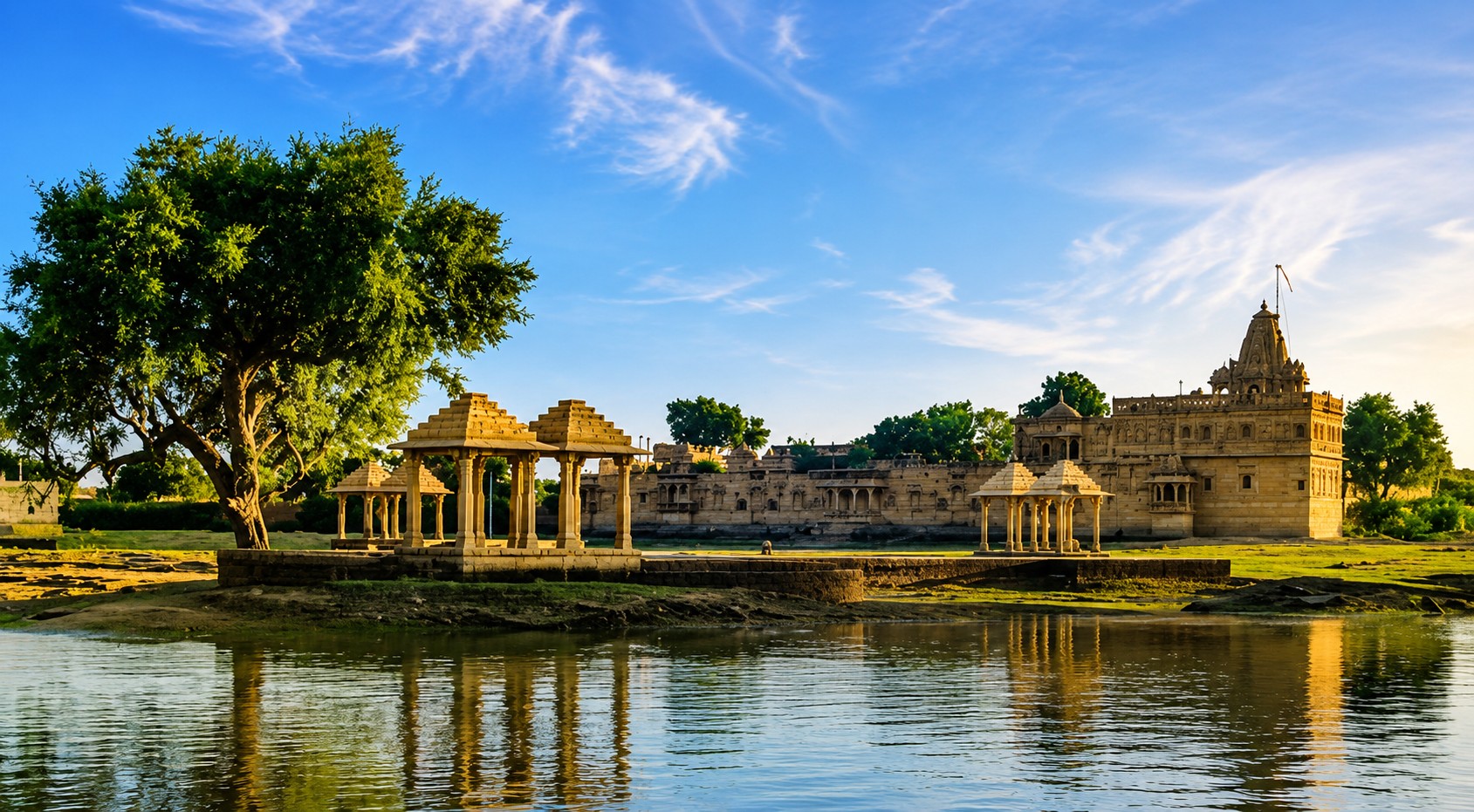 Amar Sagar lake and stone pavilions reflected in water before the Jain temple complex