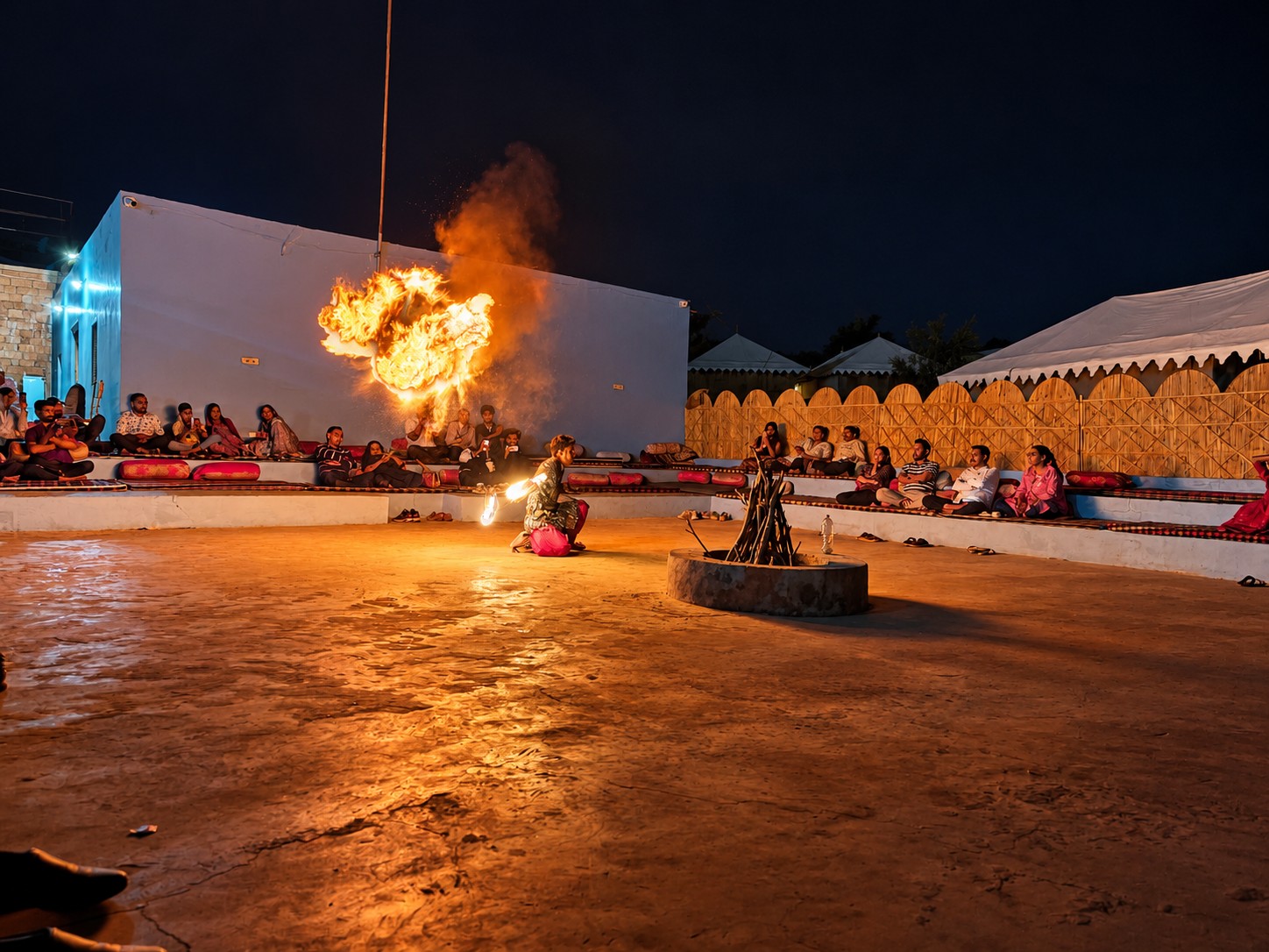 Dramatic fireside desert performance with fire breather and guests seated around the hearth